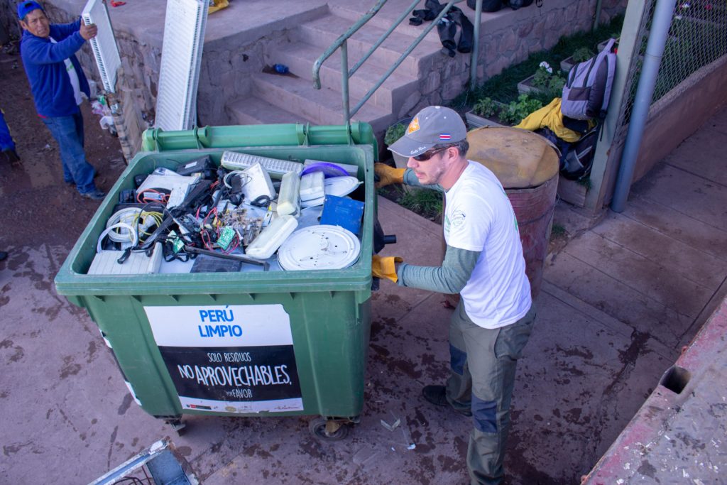 Hombre jalando un contenedor de plástico verde